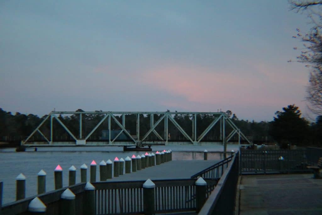 A rotating railway bridge as seen from a dock.